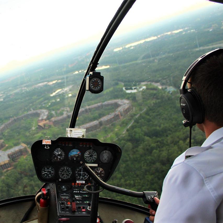 Pilot vozi helikopter s slušalkami.