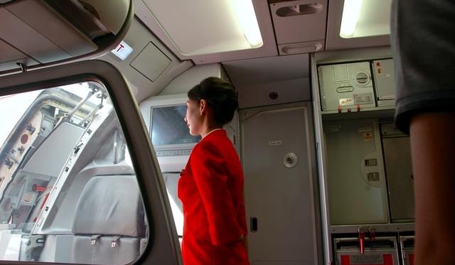 Stevardesa v rdeči uniformi gleda skozi okno letala