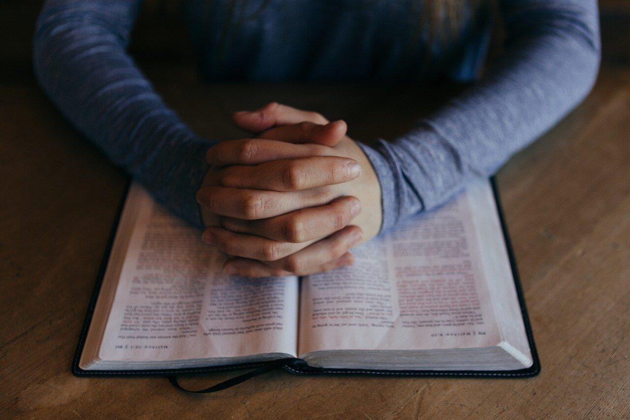 Roke, sklenjene v molitvi in knjiga.